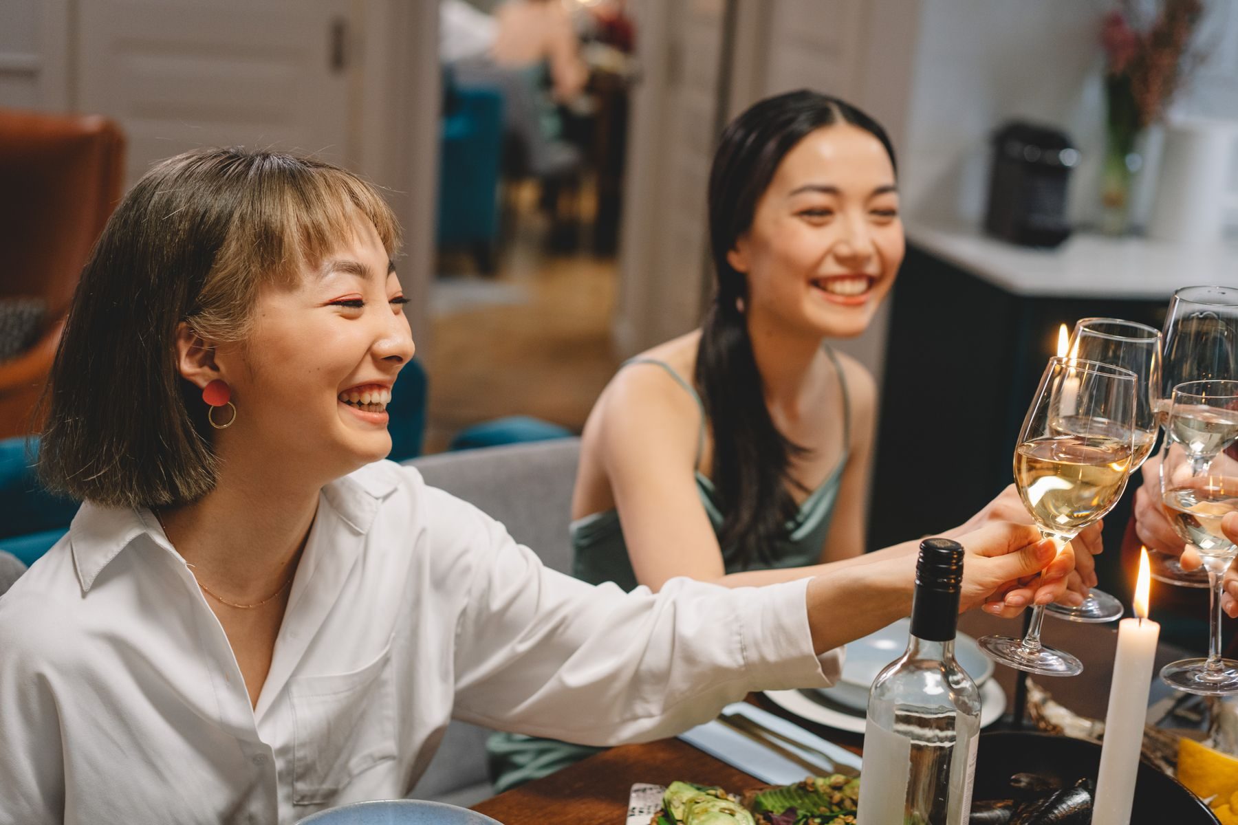 Two people laughing over a glass at a candlelit dinner table